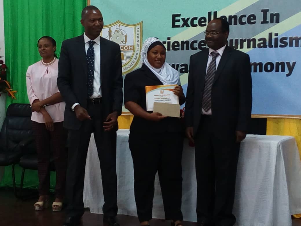 SUAMEDIA correspondent Farida Mkongwe (left) receiving prizes on behalf of Calvin Gwabara of SUAMEDIA from the permanent secretary in the Ministry of Education, Science and Technology Dr. Leornad Akwilapo(Right). Witnessing is the acting Director General of the Tanzania Commission for Science and Technology (COSTECH) Dr. Amos Nungu