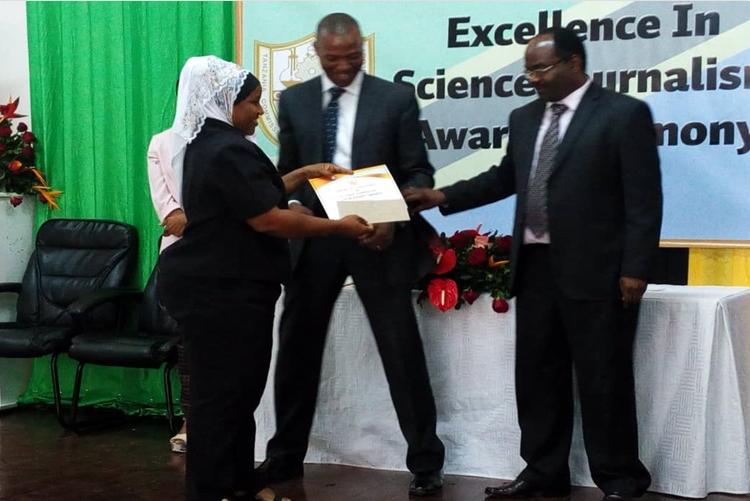 SUAMEDIA correspondent Farida Mkongwe (left) receiving prizes on behalf of Calvin Gwabara of SUAMEDIA from the permanent secretary in the Ministry of Education, Science and Technology Dr. Leornad Akwilapo(Right). Witnessing is the acting Director General of the Tanzania Commission for Science and Technology (COSTECH) Dr. Amos Nungu